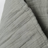 Close-up of sage muslin textured fabric with a white background