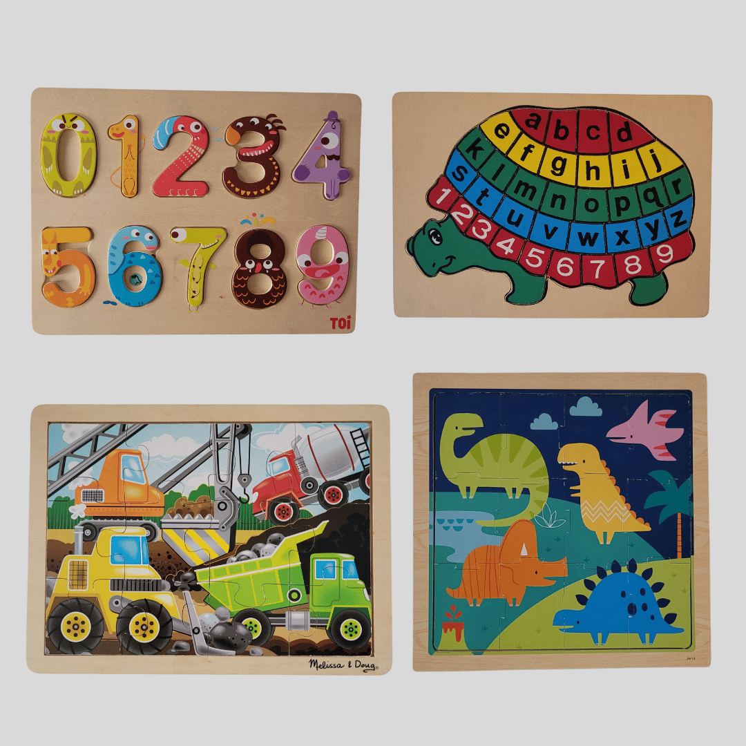 Set of four wooden puzzles with numbers, letters, construction vehicles, and dinosaurs on a white background.