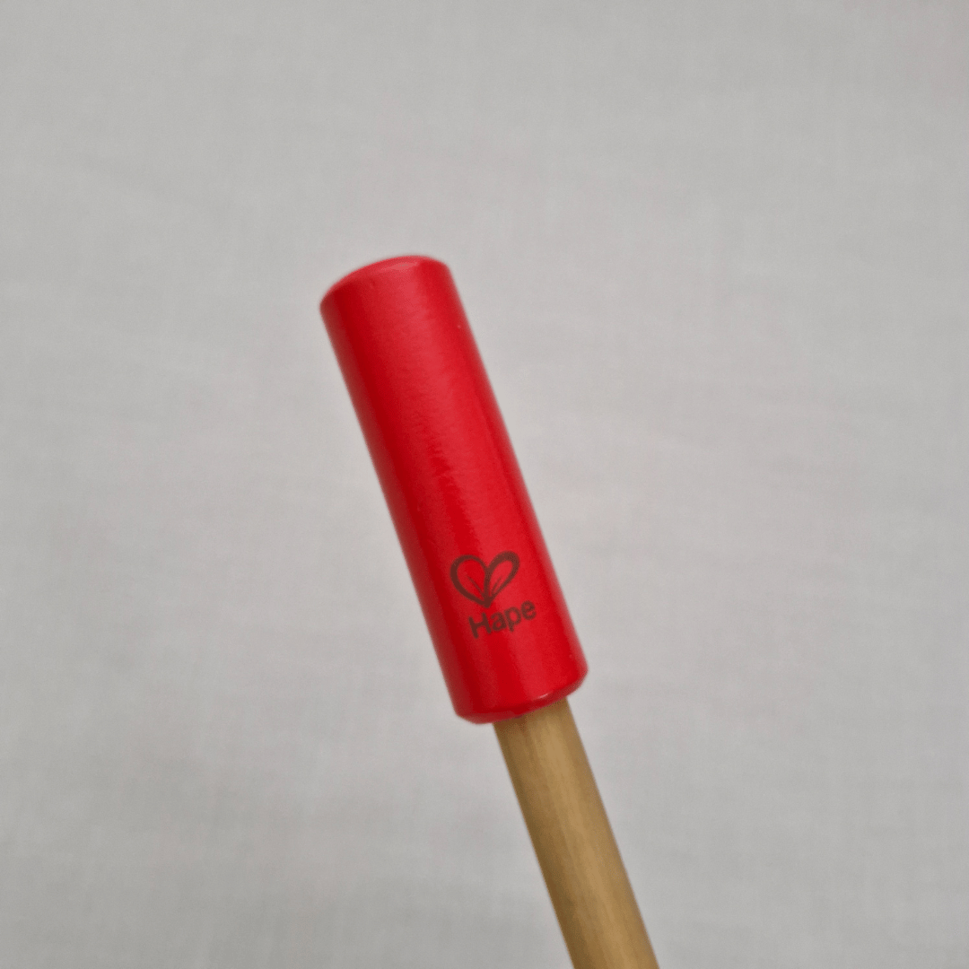 Red cylindrical object with a wooden handle on a gray background