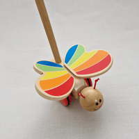 Wooden toy butterfly with colorful wings on a light gray background