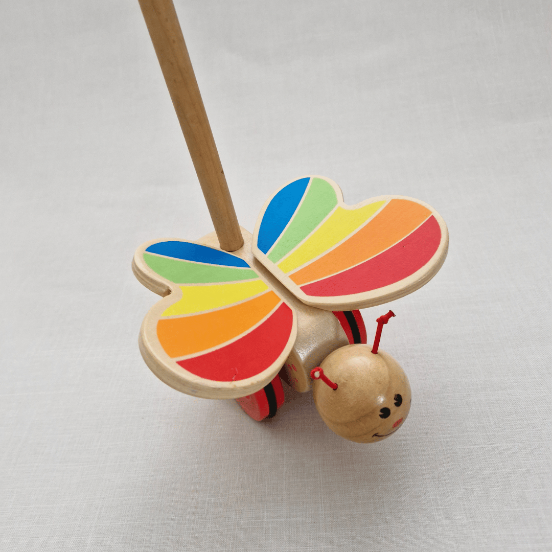 Wooden toy butterfly with colorful wings on a light gray background