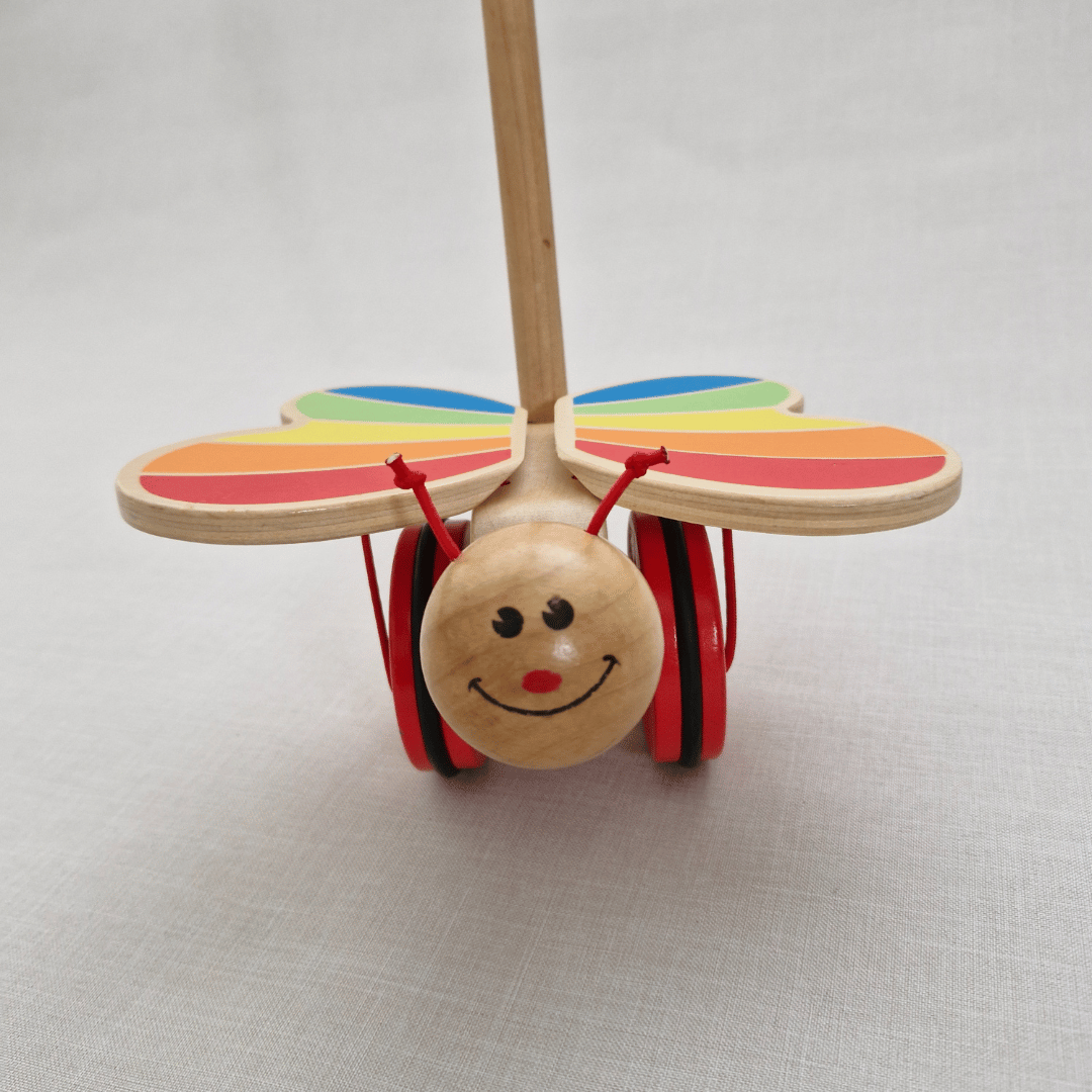 Wooden toy caterpillar with rainbow wings on a light gray background
