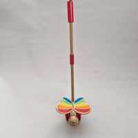 Toy with colorful butterfly wings and a red handle on a light gray background