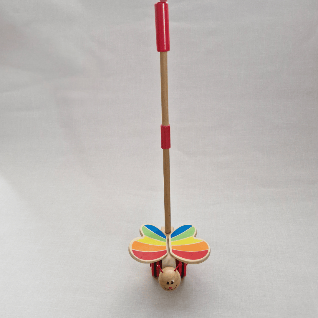 Toy with colorful butterfly wings and a red handle on a light gray background