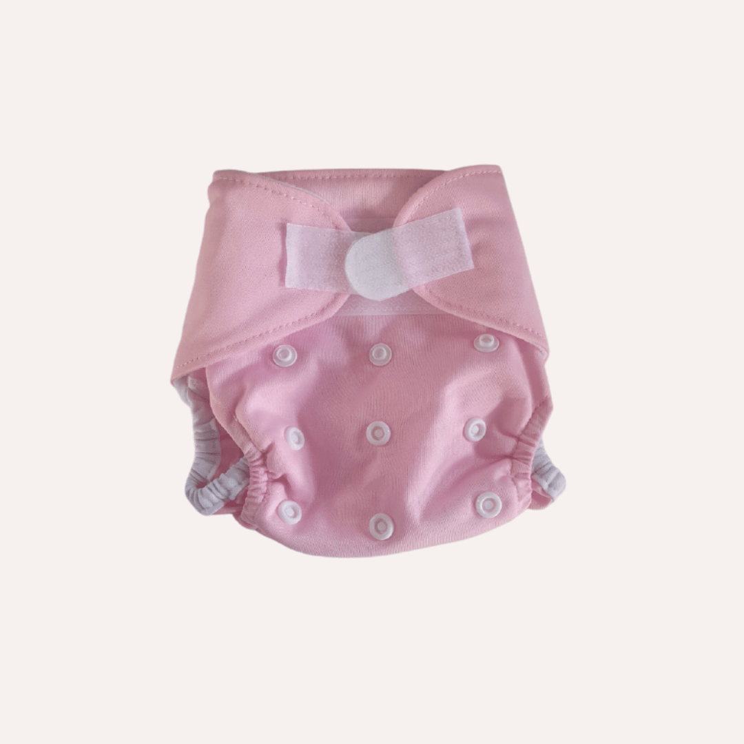 Pink newborn reusable cloth nappy with velcro on a light grey background