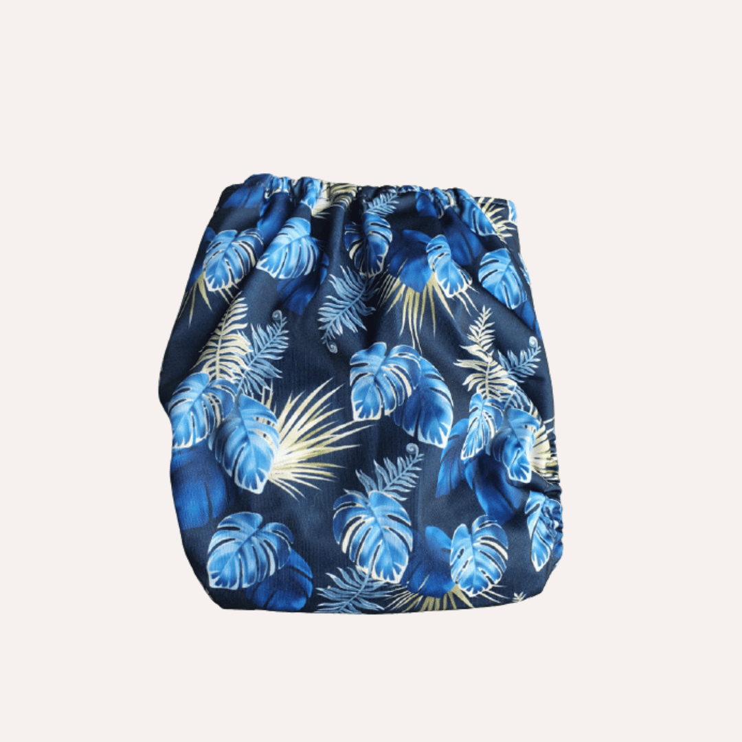Blue tropical leaf patterned reusable cloth nappy on a white background