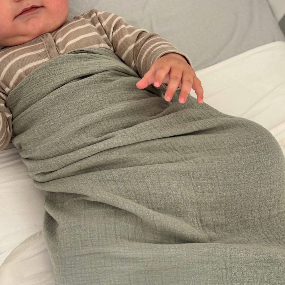 Baby wrapped in muslin swaddle blanket