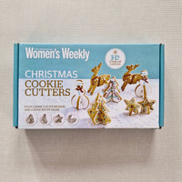 Box of Christmas cookie cutters with festive designs on a beige background