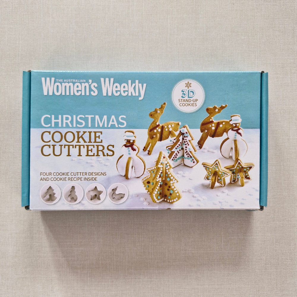 Box of Christmas cookie cutters with festive designs on a beige background