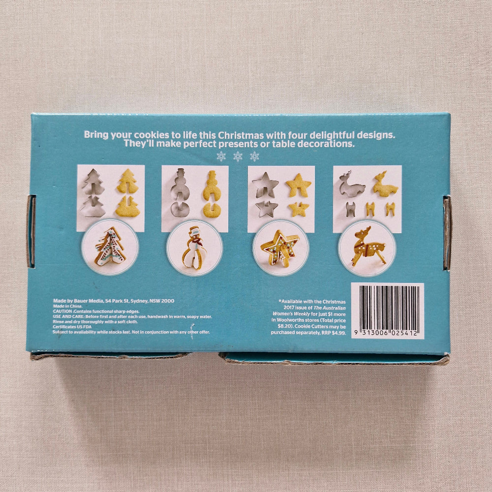 Box with Christmas-themed cookie cutters on a beige surface