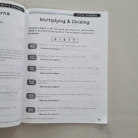 Open math workbook page on multiplying and dividing whole numbers with a gray background