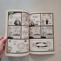 Open book with black and white comic strip pages on a light gray background