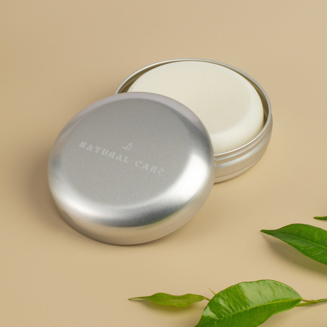 Metal tin containing a solid shampoo bar with Natural Care Logo stamped into the top