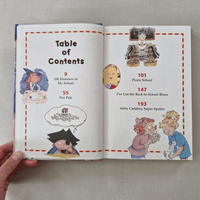 Open book showing a table of contents with illustrations and text on a grey surface.