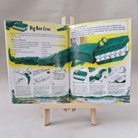Open book with instructions on creating a cardboard crocodile model, displayed on a small wooden easel.
