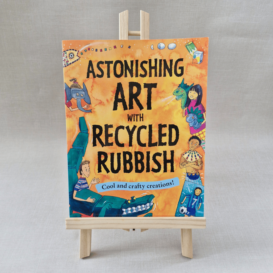 Book titled 'Astonishing Art with Recycled Rubbish' on a wooden easel against a grey background