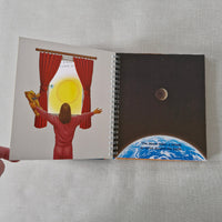 Spiral-bound book with sun and moon illustrations on a textured surface