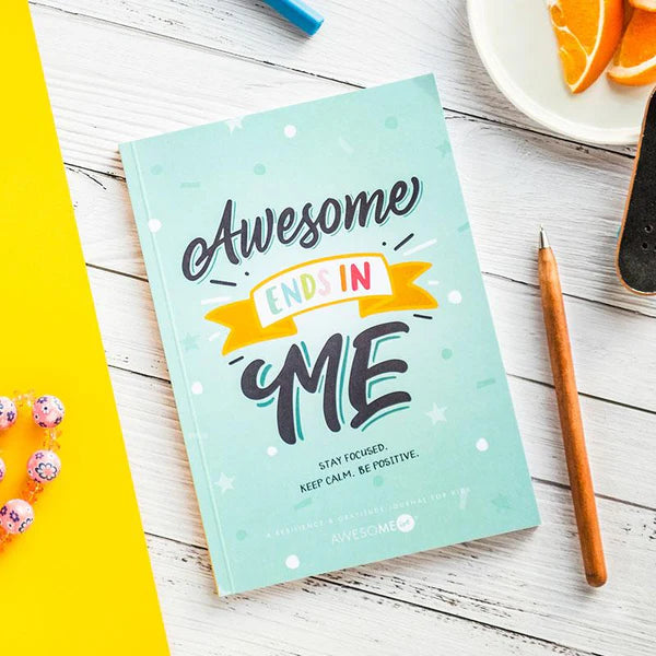 Notebook with 'Awesome Inside Me' text on a wooden surface with a pen and oranges.