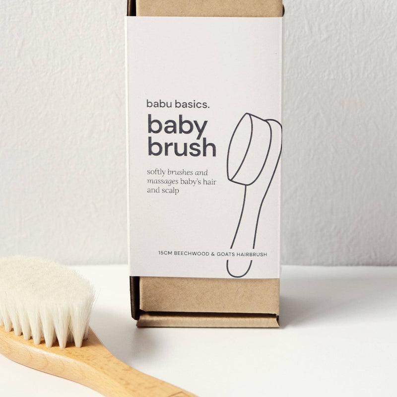 Baby brush packaging with a white label and brown box on a light grey background