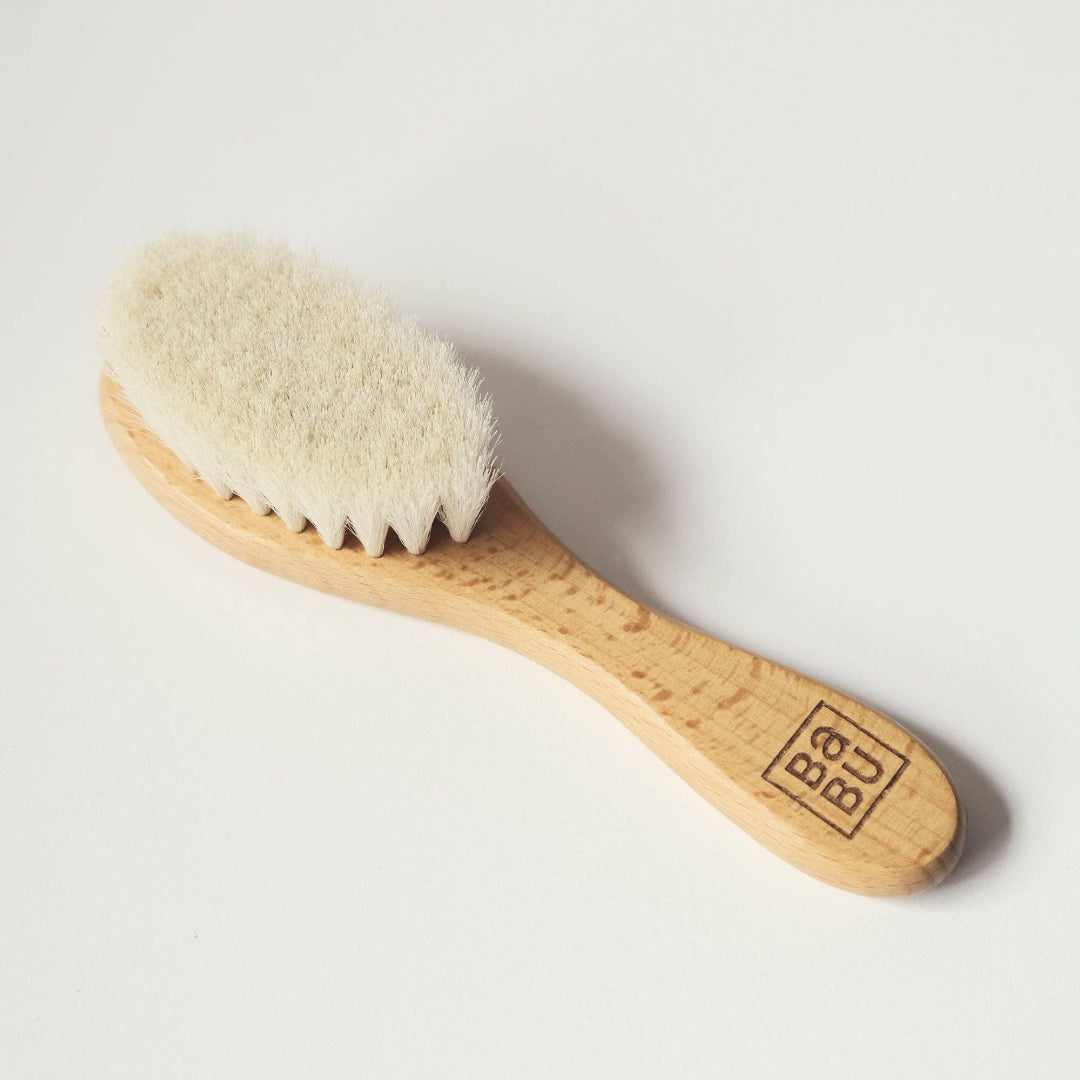 Wooden baby brush with natural bristles on a light grey background