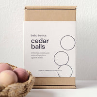 Box of babu basics cedar balls with a basket of cedar balls on a white background