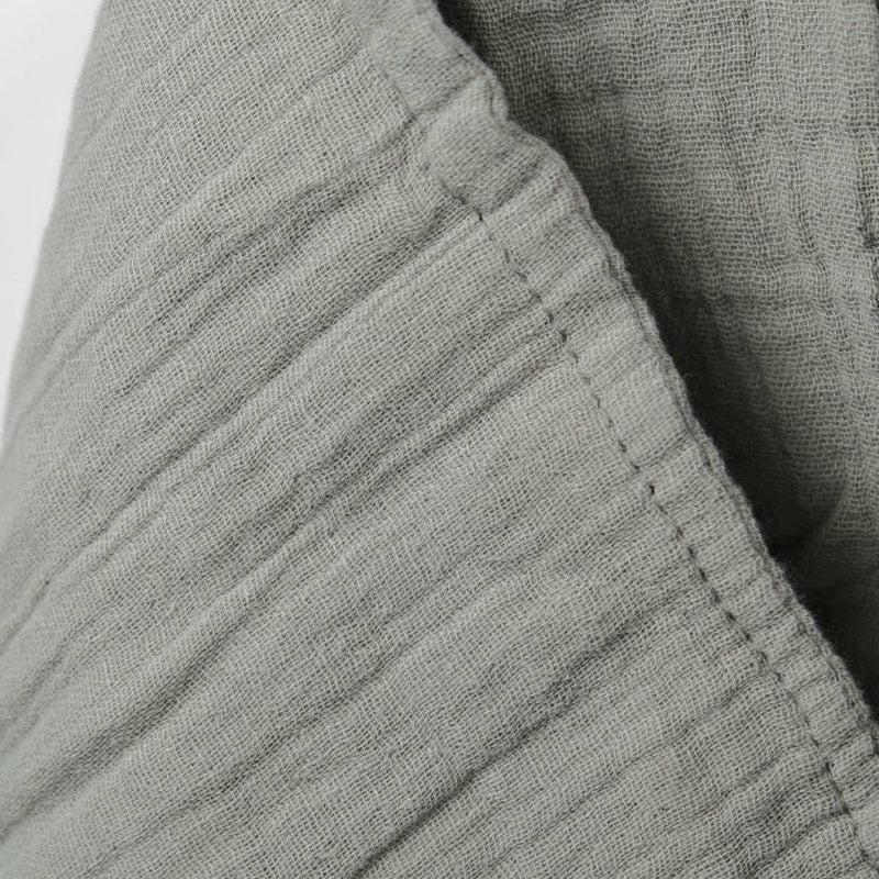 Close-up of sage muslin textured fabric with a white background