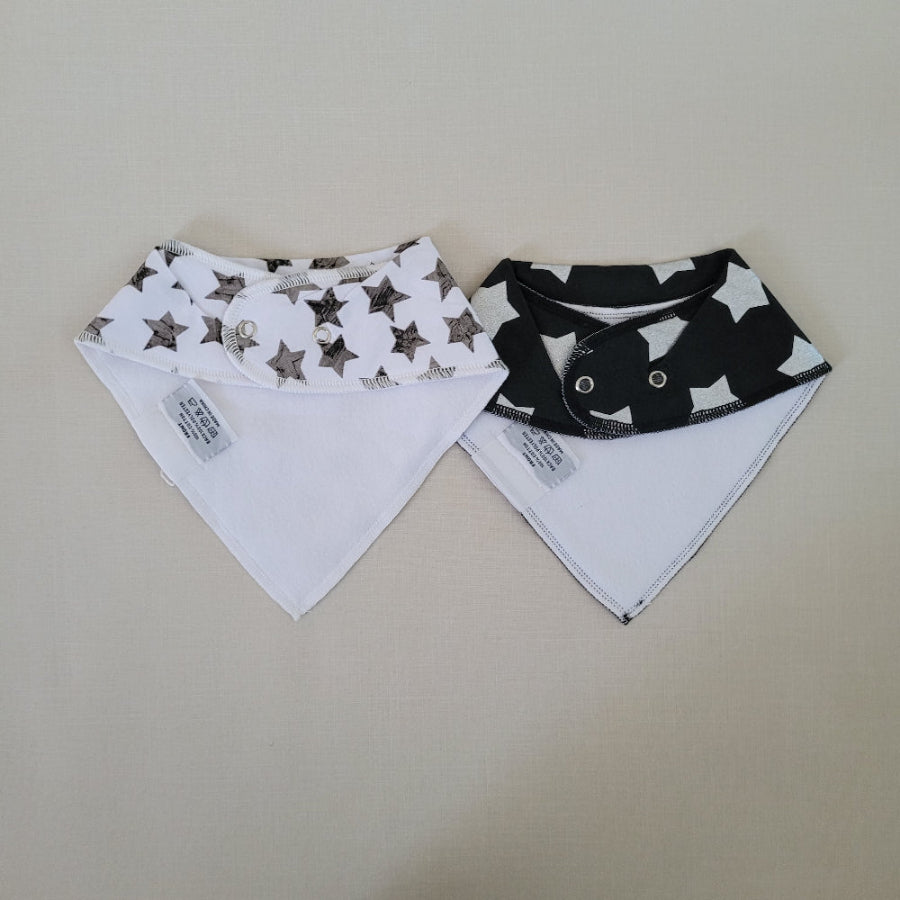 Two baby bibs with star pattern on a beige surface