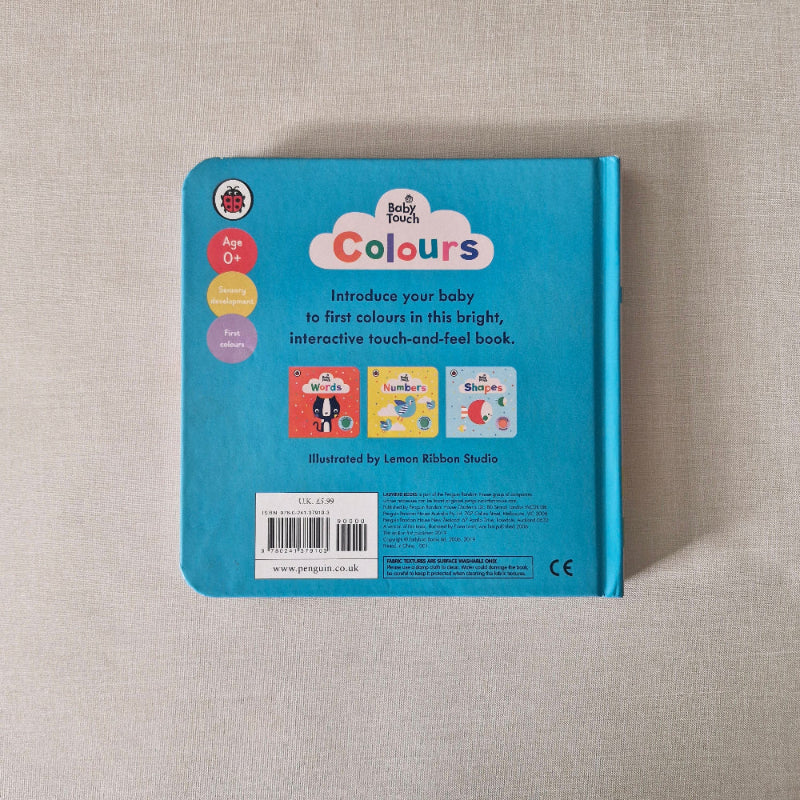 Back cover of a children's book titled 'Baby Colours' on a textured beige surface.
