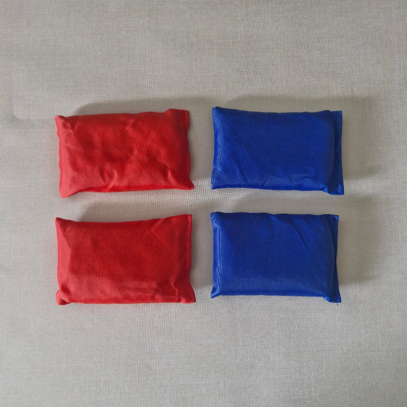 Two blue and two red fabric bean bags on a gray surface