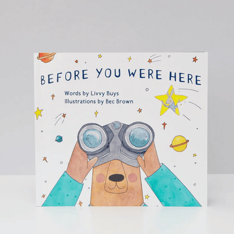 Book cover of 'Before You Were Here' with a bear holding binoculars and space-themed illustrations.