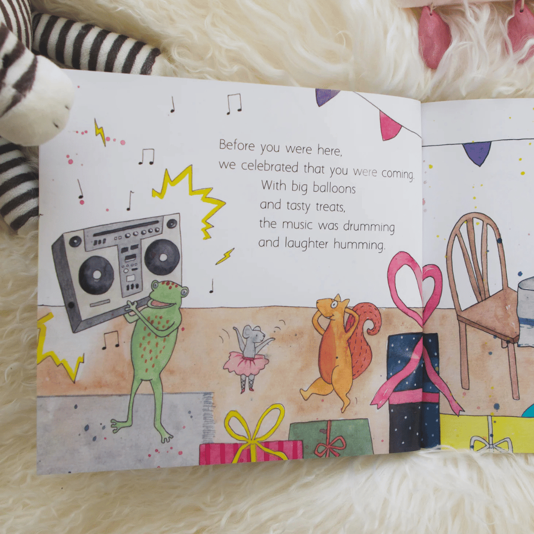 Illustrated book page with a frog, squirrel, and mouse celebrating, surrounded by balloons and music notes.