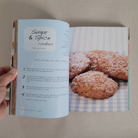 Open book showing a recipe for cookies with a close-up of cookies on a checkered cloth.