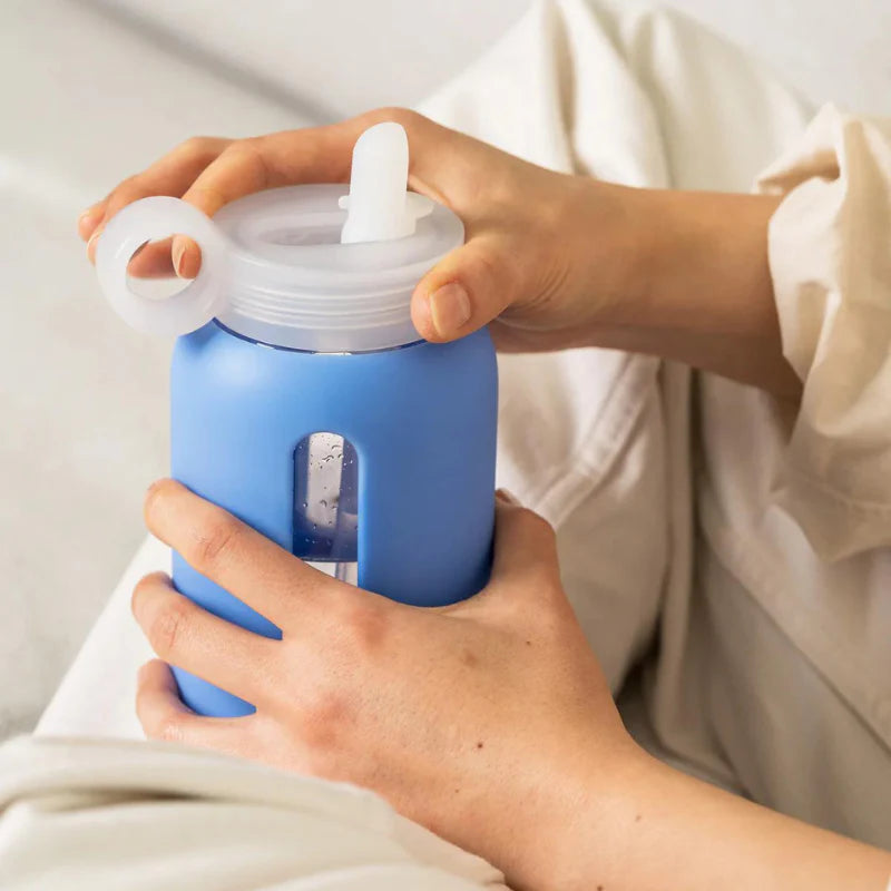 Person holding a blue water bottle with a white lid