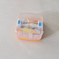 Small transparent boggle game container with dice on a light grey background