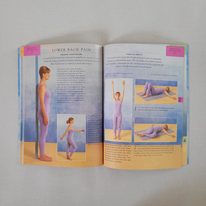 Open book showing pages with yoga illustrations and text on a plain background