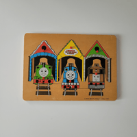 Vintage 'Thomas the Tank Engine' toy puzzle with three trains in different colored houses on a beige background.