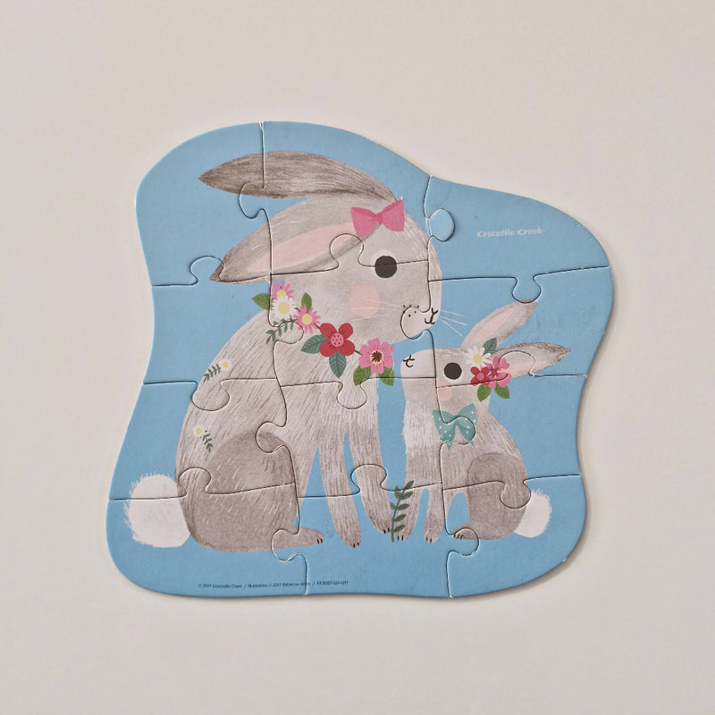 Children's puzzle with two bunnies holding flowers on a light gray background