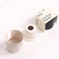 Straw and Charcoal coloured car cup holder with packaging labelled 'Bink' on a white background