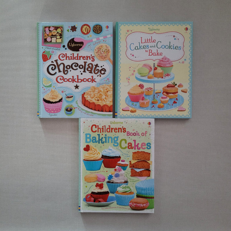 Three children's cookbooks on a gray surface
