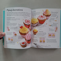 Open book with cupcake decorating instructions on a gray background