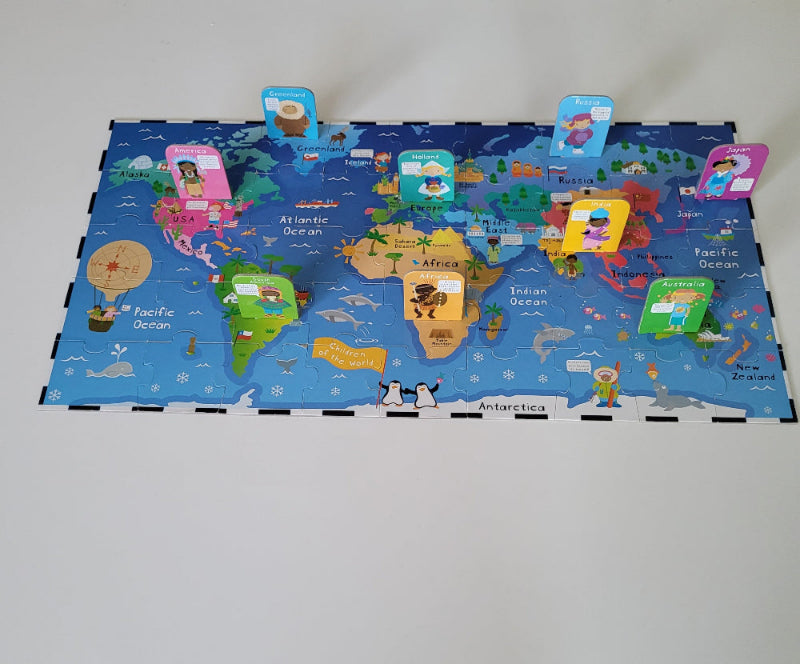 Floor puzzle depicting a world map with stand up cards placed across the different continents with figures of children on them