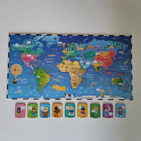 A colorful children's world map puzzle board with illustrated continents and oceans, plus nine small character tiles arranged in a row below it on a plain light background.