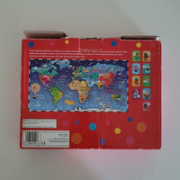 The back of a red children's jigsaw puzzle box featuring a colourful world map illustration and small puzzle icon thumbnails along the top, photographed on a light neutral background.