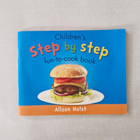 Children's cookbook titled 'Step by Step' by Alison Holst on a textured surface