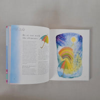 Open book with colourful illustration of a rainbow and sun on a white background