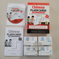 Chinese Flash Cards Volume 2 learning kit by Tuttle, including the main book, a CD, a booklet, and several character flashcards arranged on a light beige surface.