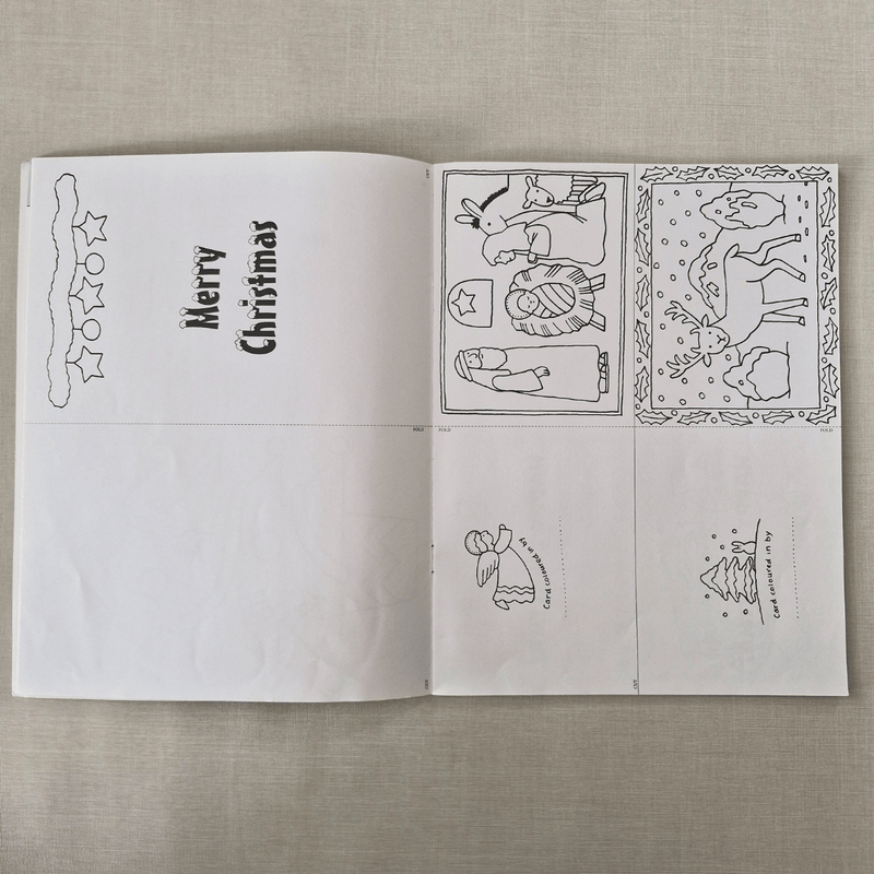 Open book with Christmas-themed line drawings on a textured surface