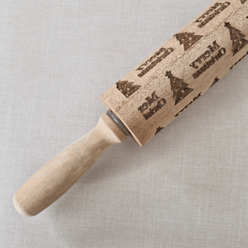 Wooden rolling pin with embossed christmas designs on a light grey background
