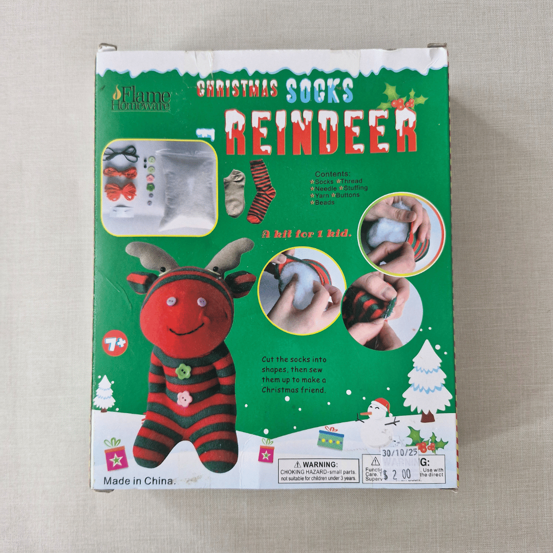 Box of reindeer-themed Christmas socks on a beige surface