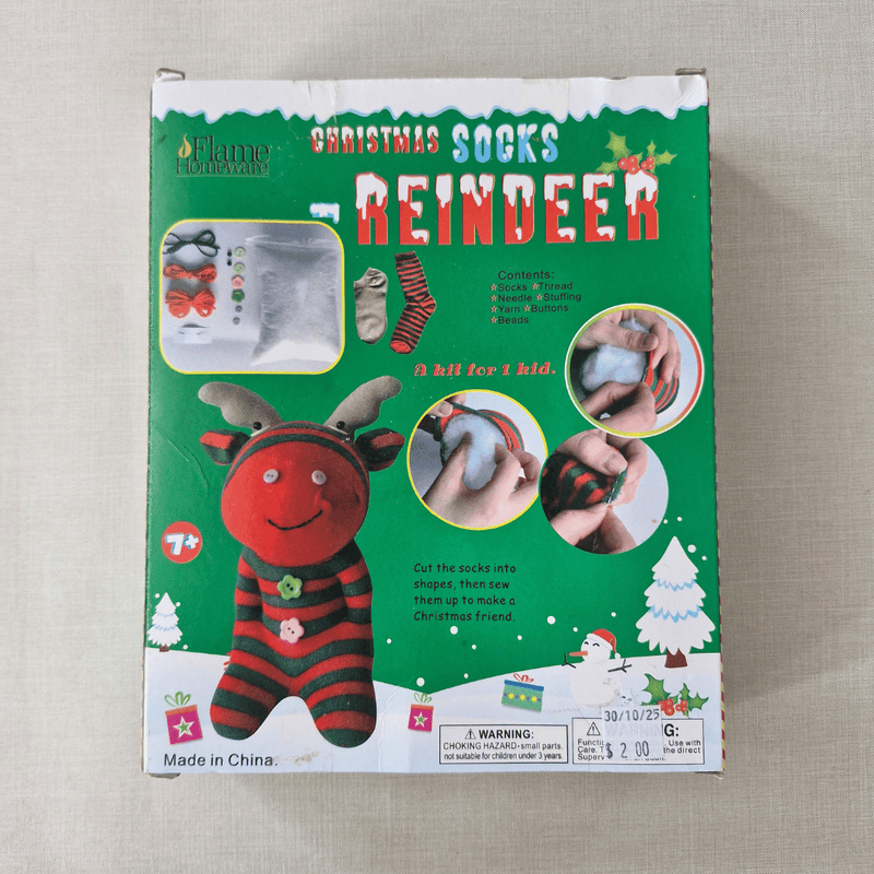 Box of reindeer-themed Christmas socks on a beige surface